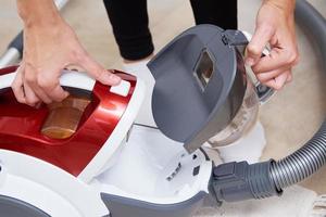 woman take out container of dust from vacuum cleaner photo