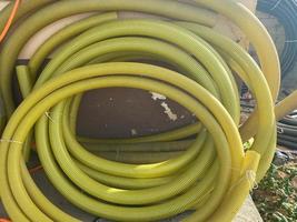 Many large coils of yellow thick plastic hoses of large diameter for pumping liquids in an industrial warehouse photo