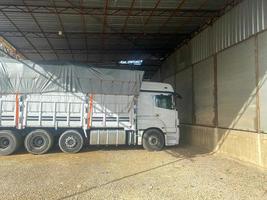 A large white powerful truck with an awning and a trailer is parked to unload cargo photo