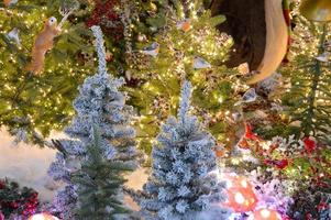 Christmas decor for a shopping center. tall fir trees in the center, decorated with bright garlands and glowing toys. artificial white spruce. glass toys on fir branches photo