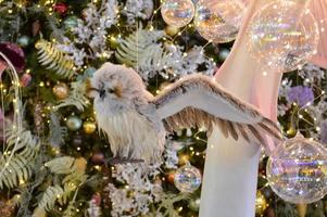 adornos navideños para el centro comercial. decoración de escaparate. búho colgando de una rama de abeto. los pájaros cuelgan de los árboles. bolas brillantes transparentes en el árbol de navidad foto
