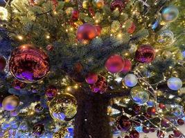 ramas verdes de un esponjoso árbol navideño festivo de año nuevo con juguetes en bolas y bombillas y guirnaldas brillantes, fondo foto