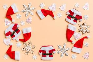 Top view of Christmas decorations and Santa hats on orange background. Happy holiday concept with copy space