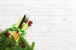 Top view of christmas decorations on wooden background. Fork and knife on napkin tied up with ribbon and empty space for your design. New year pattern concept photo