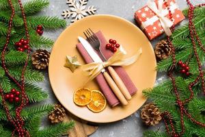 Top view of cutlery and plate on festive cement background. New Year family dinner concept. Fir tree and Christmas decorations photo