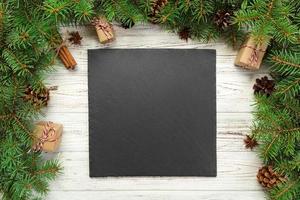 top view. Empty black slate square plate on wooden christmas background. holiday dinner dish concept with new year decor photo