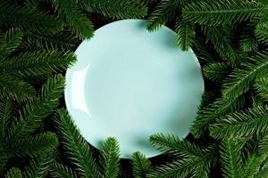 Top view holiday plate among green fir tree branches. Christmas dinner with copy space photo