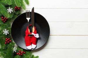 Top view of Christmas dinner on wooden background. Plate, utensil, fir tree and holiday decorations with copy space. New Year time concept photo