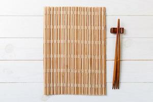 two sushi chopsticks with empty bamboo mat or wood plate on wooden Background Top view with copy stace photo