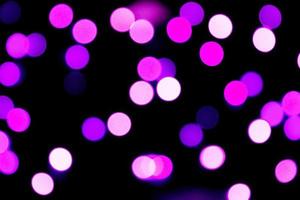 Unfocused abstract purple bokeh on black background. defocused and blurred many round light photo