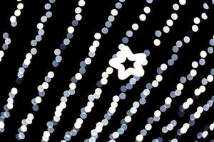 Unfocused abstract white bokeh with star of light on black background. defocused and blurred many round light photo