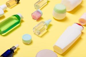 Composition of different sized cosmetic jars and bottles on yellow background. Beauty care concept with copy space photo