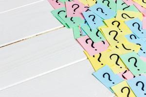 Just a lot of question marks on colored papers on wood background photo