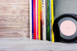 Retro styled image of a collection of old vinyl record lp's with sleeves on a wooden background. Copy space. photo