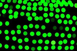 Unfocused abstract green bokeh on black background. defocused and blurred many round light photo