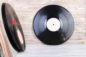 Retro styled image of a collection of old vinyl record lp's with sleeves on a wooden background. Copy space. photo