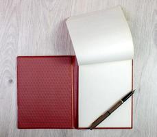 cuaderno abierto con páginas blancas y pluma estilográfica dorada foto