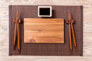 Empty rectangular wooden plate for sushi with sauce and chopsticks on wooden table, top view photo