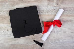 gorra de graduación, sombrero con papel de grado en concepto de graduación de mesa de madera foto