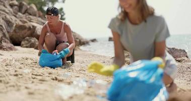 Mother And Daughter Collecting Trash On The Beach video