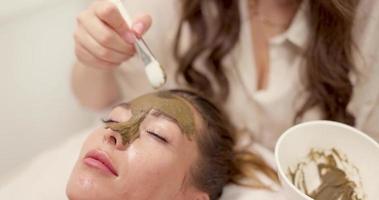 femme recevant un masque facial avec de la boue d'algues au salon de beauté video
