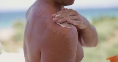 primer plano de un hombre que se aplica bronceador en el hombro. video