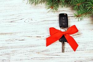 gift for christmas car keys. Close-up view of car keys with red bow as present on wooden rustic vintage background photo