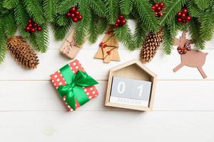 Top view of fir tree, Christmas decorations, gift and calendar on wooden background. The first of January. New year concept photo