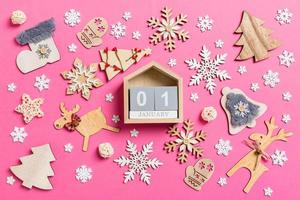 Top view of calendar on pink background made of holiday decorations and toys. Christmas ornament concept photo