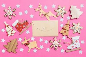 Top view of craft envelope, pink background decorated with festive toys and Christmas symbols reindeers and New Year trees. Holiday concept photo