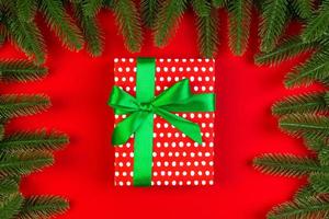 Top view of fir tree branches and gift box on colorful background. Christmas time concept with empty space for your design photo