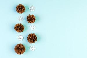 Top view of holiday composition made of pine cones and white snowflakes on colorful background. Winter time and Christmas concept with copy space photo