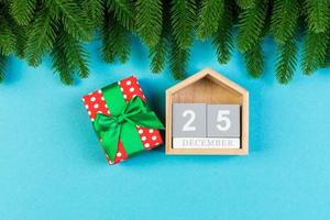 Top view of wooden calendar, gift box and fir tree on colorful background. The twenty fifth of December. Christmas time with copy space photo