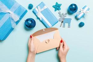 Top view of woman holding an envelope on blue background made of holiday decorations. Christmas time concept photo