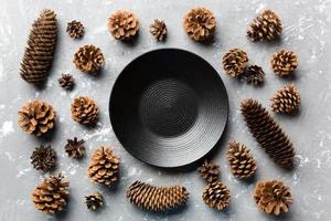 Top view of festive plate with pine cones on cement background. New Year dinner concept