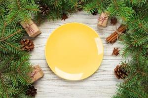 vista superior. plato vacío de cerámica redonda sobre fondo de navidad de madera. concepto de plato de cena navideña con decoración de año nuevo foto