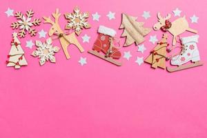 Top view of pink background decorated with festive toys and Christmas symbols reindeers and New Year trees. Holiday concept with copy space photo