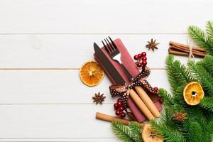 Top view of utensils on festive napkin on wooden background. Christmas decorations with dried fruits and cinnamon. New year dinner concept with copy space photo