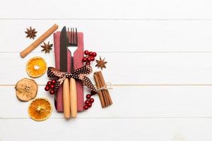 Top view of utensils on festive napkin on wooden background. Christmas decorations with dried fruits and cinnamon. New year dinner concept with copy space photo