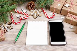 marca de teléfono inteligente portátil simulada para la época navideña, decoración navideña sobre fondo blanco, vista superior plana foto
