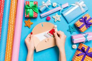 Top view of woman holding an envelope on blue background made of holiday decorations. Christmas time concept photo