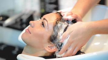 primer plano de un peluquero masculino lavando el cabello de una mujer. video