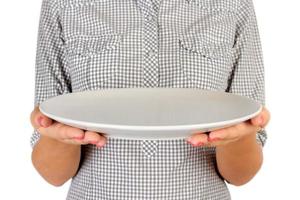 girl in the plaid shirt is holding an empty round matte plate in front of her. woman hand hold empty dish for you desing. perspective view, isolated on white background photo