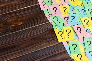 Just a lot of question marks on colored papers on wood background photo