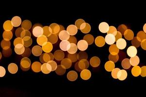 Defocused city gold night bokeh abstract background. blurred many round yellow light on dark background photo