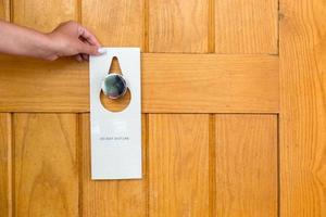 female hand hangs a sign on the door do not disturb in hotel photo