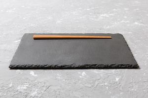 rectangular slate plate with chopsticks for sushi on black marble background photo