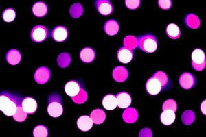 Unfocused abstract purple bokeh on black background. defocused and blurred many round light photo