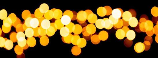 Holiday glowing gold backdrop. defocused and blurred many round yellow light on Christmas black background photo