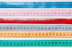 Close up of a group of colorful measure tapes lying in rows as a background. Diet concept on wooden background photo